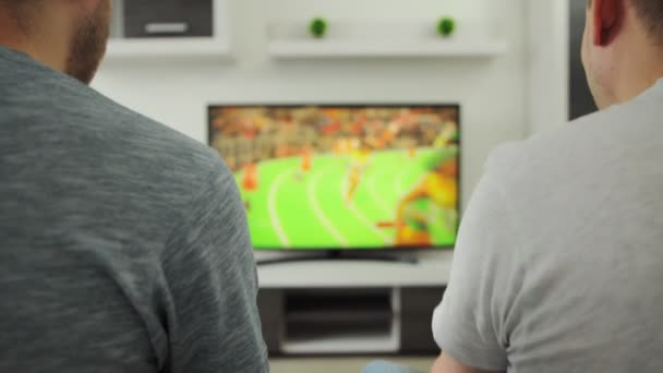 2 Mannen fans zitten op de bank in de kamer thuis en kijken sportevenement op tv. Zomerwedstrijd. Atletiek loopt 2021. Rooters fans kijken naar plasma-uitzendingen in het moderne interieur. Stroomt. Wedden? Tokio — Stockvideo