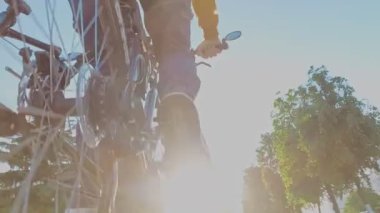 Adam şehirde MTB bisikleti sürüyor. Tekerlek yakın çekim. Zincirleme sürüş, arka raydan çıkarıcı ve kaset. Dağ bisikletinin vitesi. Jokey tekerlekleri, aylak aylak aşağı ve yukarı makaralı. Cogset dişlileri. Vites değiştir.