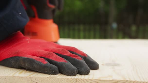 A man polishes wood with a power tool, a close-up. Handmade wood, cleaning wood with sandpaper — Stock Video