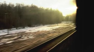 Tren yolunda araba sürerken tren penceresinden ve gökyüzünde güneşli bir günbatımı, arka plan. Ulaşım