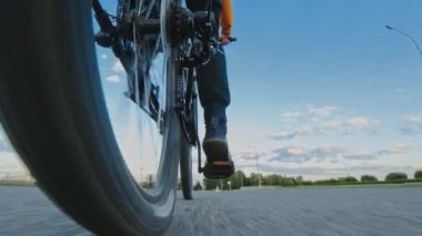 Adam şehir dışında MTB bisikleti sürüyor. Tekerlek yakın çekim. Zincirleme sürüş, arka raydan çıkarıcı ve kaset. Dağ bisikletinin vitesi. Jokey tekerlekleri, aylak aylak aşağı ve yukarı makaralı. Cogset dişlileri. Vites değiştir.