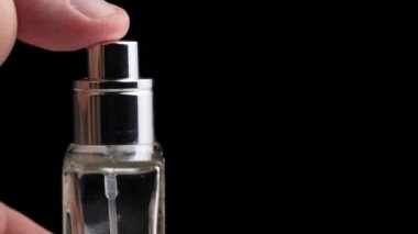 Erkek, siyah arka planda parfüm dağıtıcısına el basar. Metin, yakın plan, aroma için boşluk kopyala