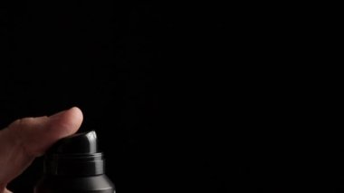 Siyah arka planda bir deodorant spreyi sıkıyor. Saç spreyi konsepti, sprey jet, makro. Yavaş çekim, metin için alanı kopyala
