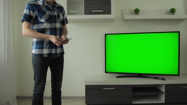 L'uomo conta i soldi in mano vicino alla TV a casa. Cromakey schermo verde. Concetto di scommessa, scommessa. Successo finanziario e di investimento nel mercato delle monete cripto. Moderna camera appartamento interno — Video Stock