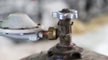 Bir adam bir gaz tüpünün vanasını eliyle kapatıyor, yakın plan, ekipman.