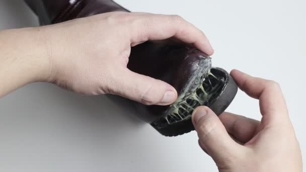 En skoreparatör limmar fast sulan på en dams vinterkänga. Låg kvalitet skor koncept, stövlar reparation, närbild — Stockvideo