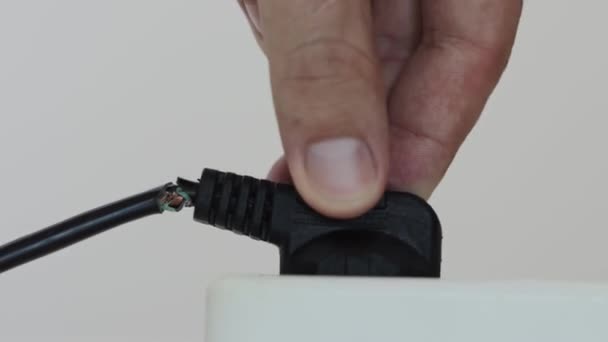 Een mans hand steekt een draad met beschadigde isolatie in een stopcontact. Veiligheidsovertreding concept, elektrische schok. Close-up — Stockvideo
