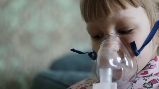 Маленькая девочка дышит лекарством от туманности, когда кашляет. Лечение легких детей с ингаляцией, крупным планом — стоковое видео
