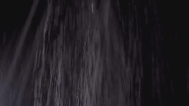 Реактивные струи воды, льющиеся на черном фоне. Дождь льется вниз, текстура — стоковое видео