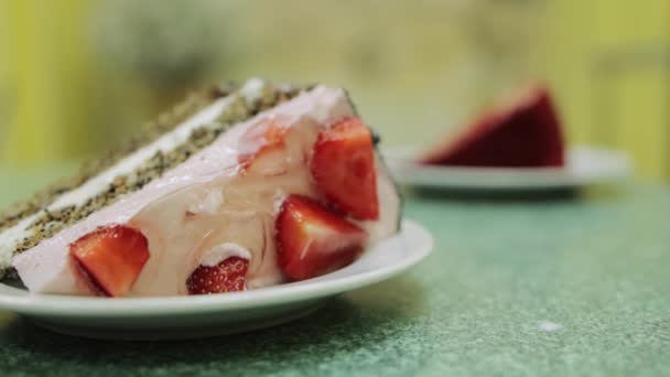 Dos pedazos de pastel con fresas frescas y crema batida en una mesa en un café. Dulce y delicioso postre, primer plano — Vídeos de Stock