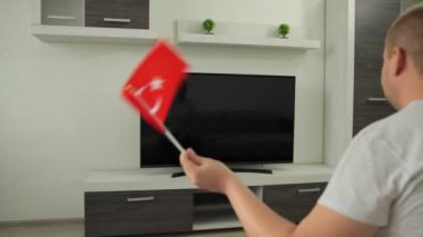 Spor taraftarı evinde TV karşısında oturuyor, Türkiye bayrağını sallıyor ve Yaz Kış Oyunları 'nda milli takımın zaferini kutluyor. Adam dünya şampiyonası kupasının yayınını izliyor. Kazan.