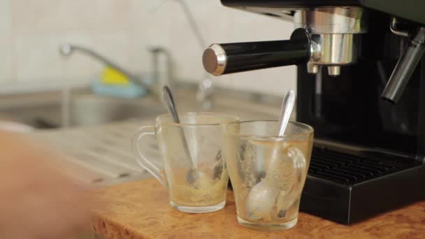 Un hombre pone dos tazas sucias en el fregadero después de beber café en la cocina contra el fondo de una cafetera, primer plano — Vídeos de Stock