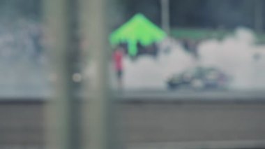 Gösteri sırasında iki araba asfalt yolda keskin virajlarda sürüklenir. Tekerleklerin altından duman çıkıyor. Lastik patlamış. Ağır çekimde yarış yarışmaları. Seyirciler performansı izliyor. Bulanık. Ekstrem sürüş