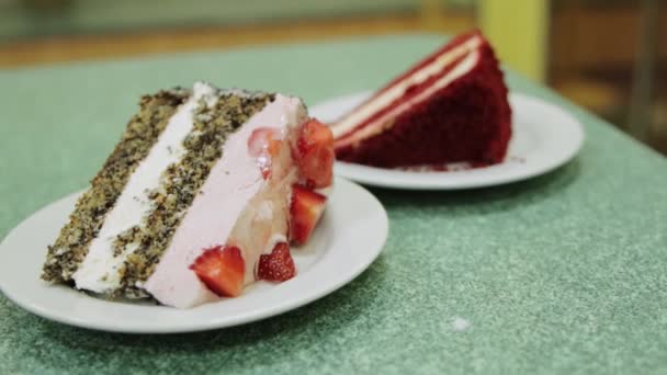 신선 한 딸기와 크림을 곁들인 케이크 두 조각 이 카페에 있는 테이블에 있습니다. 달콤하고 맛있는 디저트, 클로즈업 — 비디오