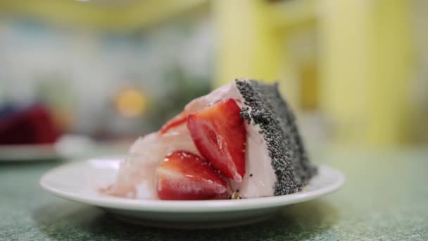 Hombre comiendo un pedazo de pastel con fresas frescas y semillas de amapola en un café, de cerca. Comer postre, time-lapse — Vídeos de Stock