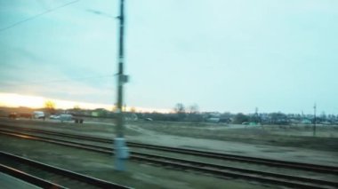 Tren yolunda araba sürerken tren penceresinden ve gökyüzünde güneşli bir günbatımı, arka plan. Ulaşım
