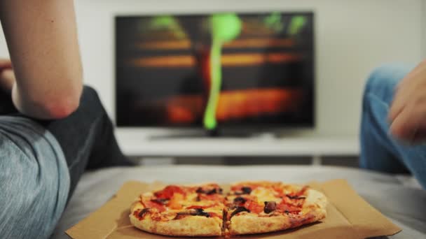 2 amigos estão sentados no sofá, comendo pizza, assistindo filme na TV em casa. Lazer de gays de família, homossexuais. Lgbt casal. Fim de semana, férias, fim de semana de trabalho. Estilo de vida prejudicial, nutrição. Descanso — Vídeo de Stock