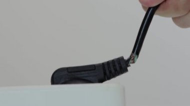 Bir adam kötü izole edilmiş bir prizden hasarlı bir elektrik kablosunu rastgele çıkarır. Elektrik şoku, güvenlik ihlali, yakın çekim.