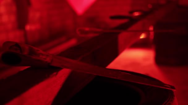 Many hacksaws lie in a dim, red-lit room. Eerie environment. Killing preparation concept, close-up — Stock Video