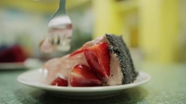 Bir kafede taze çilek ve haşhaş tohumlu kek yiyen bir adam, yakın plan. Tatlı yemek.