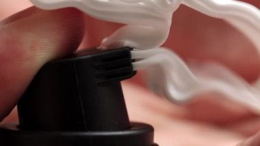 Adamın eli teneke kutuya basar ve tıraş köpüğünü sıkar. Siyah arka plan, makro. Kozmetik, yavaş çekim