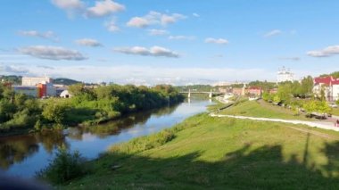 Şehirde güzel bir manzara nehir akar, bir tepenin üzerinde mavi gökyüzünün arka planında bir kilise vardır. Yazın yeşil çimen ve manzara. Metin için alanı kopyala