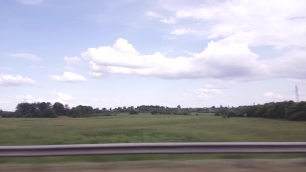 The view from the car window to the fields and meadows. Beautiful nature on a background of blue sky with clouds. Journey, copy space for text — Stock Video