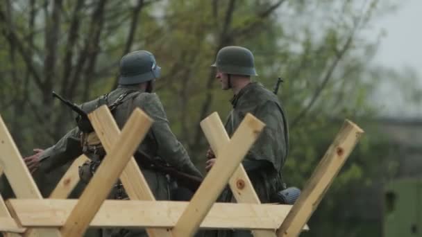 2 Wehrmacht soldaten in Duits legeruniform praten met elkaar tijdens de wederopbouw van de gebeurtenissen van de Tweede Wereldoorlog aan het Oostfront tegen de USSR. Nazisme fascisme concept. moffen wachten op de strijd — Stockvideo