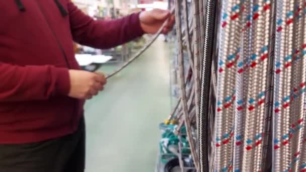 Muž v instalatérském obchodě vybírá hadice do domu. Prodej stavebních materiálů, zázemí. Detailní záběr — Stock video