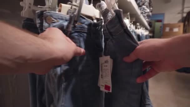 Un uomo sceglie pantaloni jeans in un negozio. Abbigliamento concetto di shopping, primo piano, alla moda — Video Stock