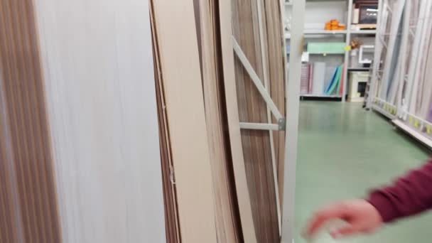 Mężczyzna kupujący wybiera drewnianą sklejkę do dekoracji wnętrz w sklepie z materiałami budowlanymi, zbliżenie — Wideo stockowe