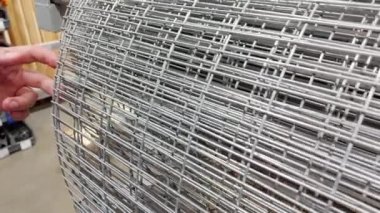 A man chooses a metal reinforcing mesh in a building materials store, close-up