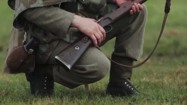 Soldier in uniform of Wehrmacht of German army during World War II sits and holds rifle gun in hands waiting for battle during reconstruction of invasion to USSR 22 June 1941 in Soviet Union. Closeup — Video