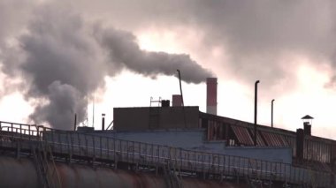 Fabrikanın bacalarından akşam gökyüzünün arka planına doğru büyük duman ve buhar yükseliyor, endüstri. Üretim