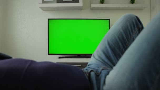 Man ligger på soffan och tittar erotisk videokanal hemma på TV. Killen lägger handen i jeansen och rör vid könsorganen. Sexuellt beroende. Hypersexualitet. Virtuellt online sex ensam. Onani. XXX — Stockvideo