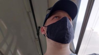Koruyucu tıbbi maske takan bir adam toplu taşıma araçlarına biniyor. Enfeksiyon ve koronavirüse karşı solunum koruması kavramı, yakın plan.