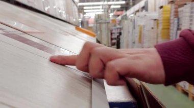 Bir adam seramik fayansları bir mağazada yenilemek için seçer. Yapı malzemeleri deposu