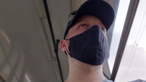 A man wearing a protective medical mask rides on public transport. Respiratory protection concept against infections and coronavirus, close-up — Stock Video