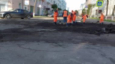 Yol işçileri yolu onarıyor, yollardaki boşlukları dolduruyor ve yeni asfalt döşüyorlar. Bulanık, arkaplan