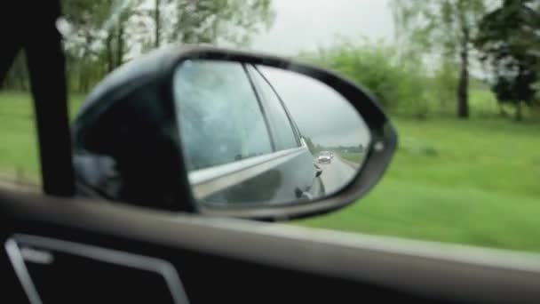 Πίσω καθρέφτης ενός αυτοκινήτου σε βροχερό καιρό στο δρόμο. Πίσω από ένα διερχόμενο αυτοκίνητο, κοντινό — Αρχείο Βίντεο