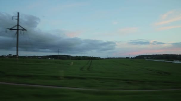 Vista desde la ventana del coche en un viaje. Tarde hermoso cielo y campos con hierba. Copiar espacio para texto, paisaje — Vídeos de Stock