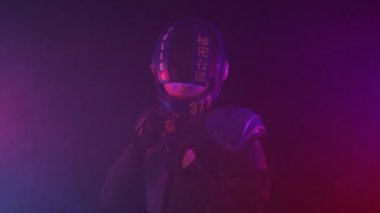 Siberpunk gelecek konsepti. Polis memuru yumruklarıyla boks pozisyonunda duruyor. Halfman robotu karanlıkta dumanla savaşmaya hazır. Biyonik sayborg kameraya bakıyor. Kırmızı mavi ışık yanıp sönüyor. Portre