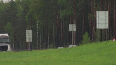 Yol kamyonları kötü yağmurlu havada mal taşır. Direksiyonun altından çok sular aktı. Su yüzünden kaygan bir yolun tehlikesi
