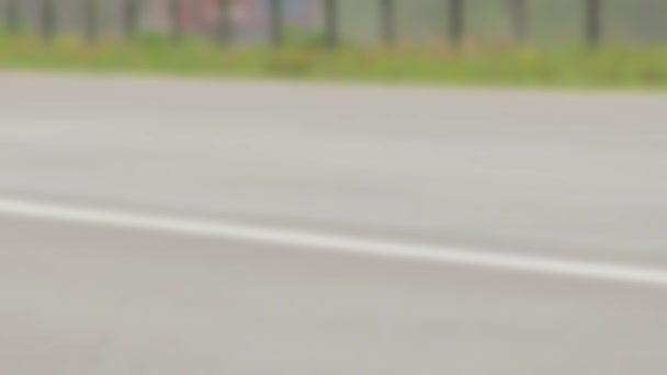 The wheels of a passenger car drive along the wet asphalt of the motorway in the background rain. Blurry, copy space for text — Stock Video