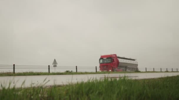 A gleaming semitrailer tank truck transports liquid cargo in bad rainy weather. Copy space for text. Slow motion — Stock Video