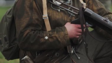 2. Dünya Savaşı sırasında Alman ordusunun Wehrmacht üniforması giyen asker, 22 Haziran 1941 'de SSCB' ye yapılan saldırının yeniden yapılandırılması sırasında çarpışmayı bekleyen maschinenpistole tabancasını parmaklarıyla zafer işareti olarak gösterdi.
