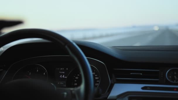 Een dashboard dat het brandstofverbruik in de auto weergeeft. Rij in de winter op de snelweg, achtergrond. Langzame beweging — Stockvideo