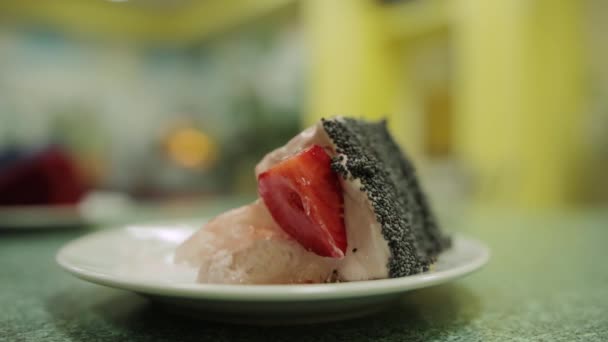 Man eating a piece of cake with fresh strawberries and poppy seeds in a cafe, close-up. Eating dessert — Stock Video