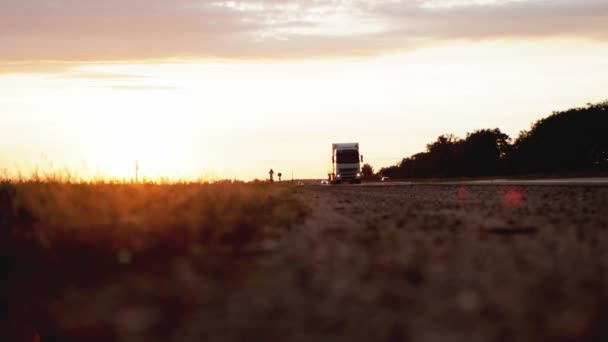 Ciężarówka z przyczepą przewozi ładunki grupowe na autostradzie w tle zachodu słońca. Koncepcja klasyfikacji transportowanych towarów, logistyki, przeładunku, jesień — Wideo stockowe