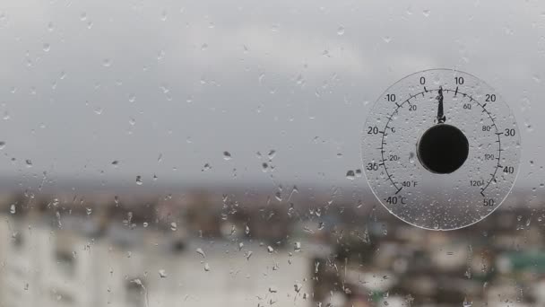 Термометр наружной температуры при падении за окном. Плохая дождливая и ветреная погода. Копирование текста — стоковое видео